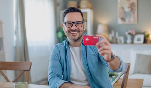 hombre feliz mostrando tarjeta La Roja de BAC