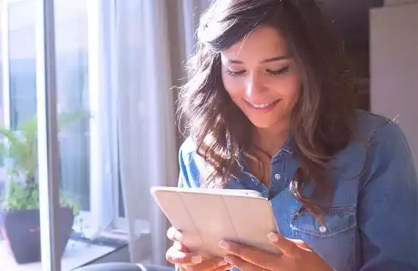 Joven con una tableta en la manos viéndola.