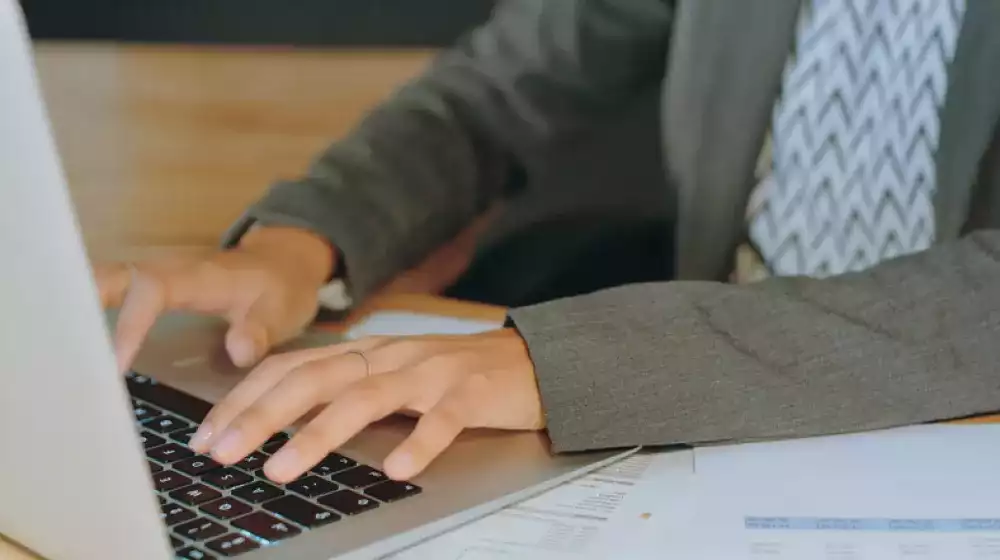 Manos escribiendo en teclado de computadora portátil