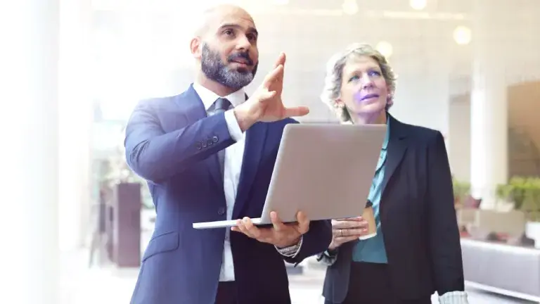 Pareja de empresarios con computadora visualizan su proyección a futuro