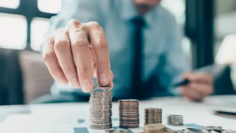 Empresario formando columnas de monedas en orden creciente