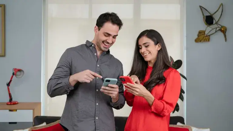Pareja hombre y mujer miran felices sus celulares 